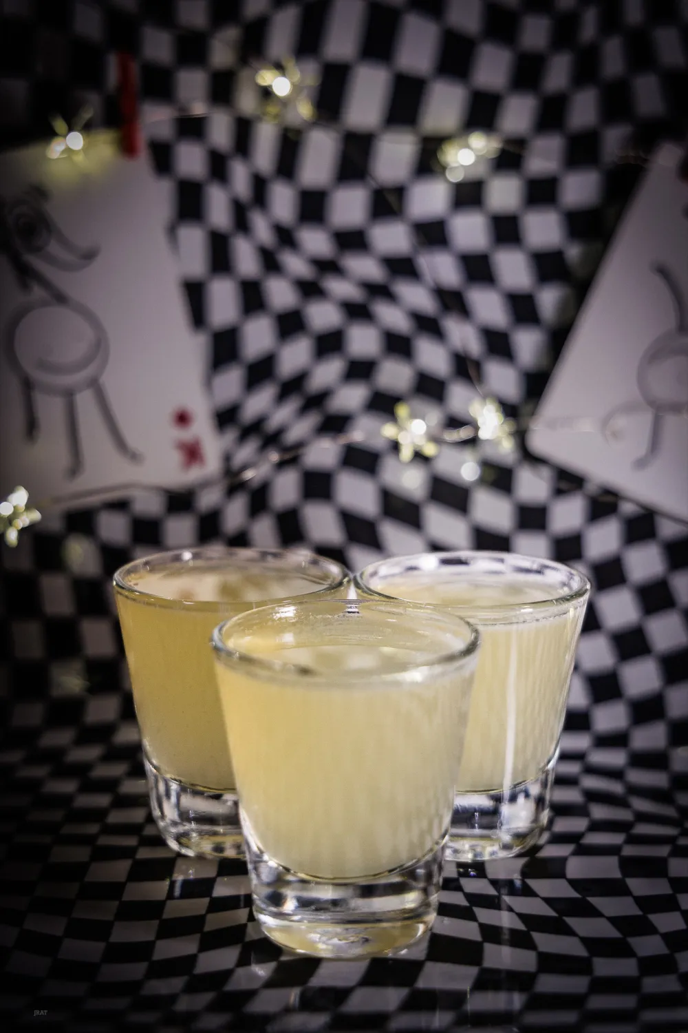 Three green tea shots on a checkerboard backdrop