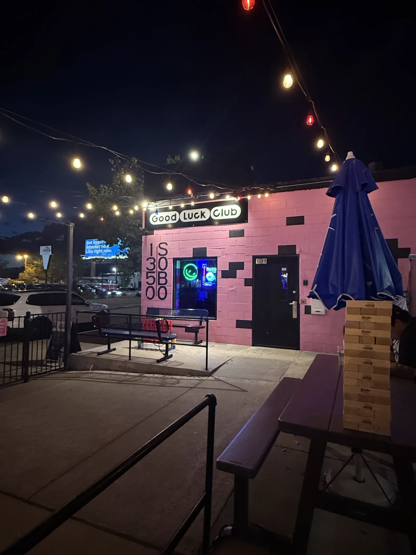 The patio at night under string lights, the pink wall behind it
