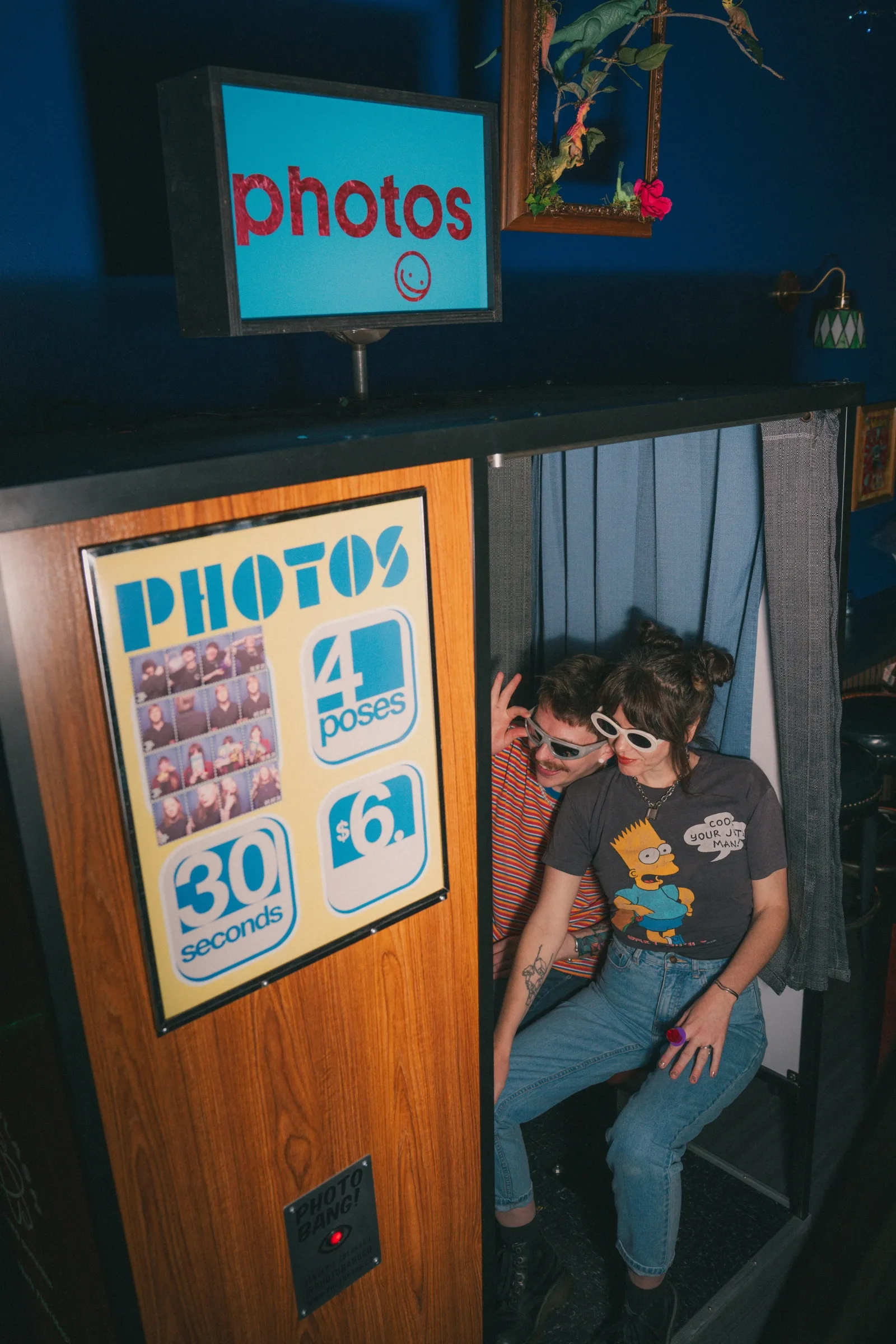 Two friends in sunglasses squeezed into the photo booth