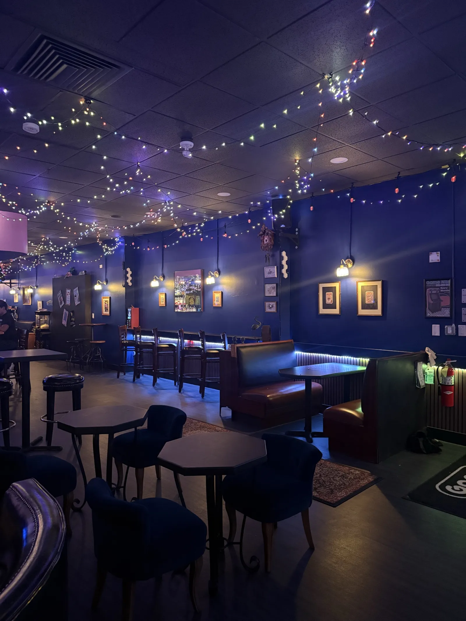 The bar room under strings of Christmas lights, booths along the wall
